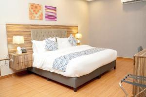 una habitación con una cama grande con sábanas y almohadas blancas en Palette Luxury Credi Hotel, en Riad