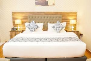 Un dormitorio con una gran cama blanca con dos almohadas. en Palette Luxury Credi Hotel, en Riad