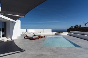 a patio with a pool and chairs and the ocean at Oikos Santorini Living Concept in Fira