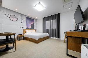 全州市にあるJeonju Raon Hotelのベッドと机とテレビのある寝室