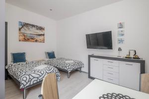 a living room with two beds and a flat screen tv at Hostel Gdynia - Pokoje 2-osobowe na wyłączność in Gdynia