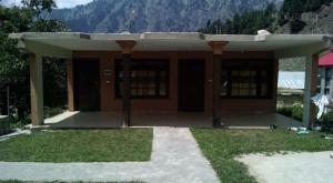 a small house with a porch with mountains in the background at Star Rise Hotel in Naran