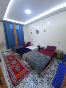 a bedroom with two beds and a rug at Dar Kawtar in Marrakesh +49 photos