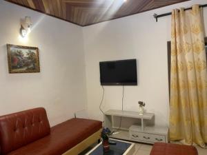 Una sala de estar con un sofá y un televisor de pantalla plana. en King's home, en Yaoundé