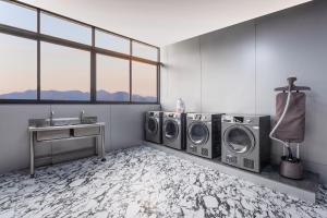 een wasruimte met 3 wasmachines en een wastafel bij Jingyue Yaduo Hotel in Yiwu