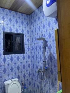 y baño de azulejos azules con aseo y ducha. en King's home, en Yaoundé