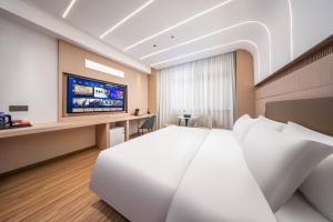 een hotelkamer met een bed en een flatscreen-tv bij Jingyue Yaduo Hotel in Yiwu