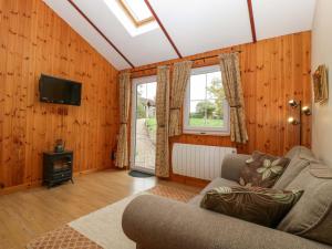 a living room with a couch and a tv at The Log Cabin in Gloucester