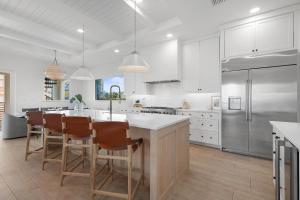 a kitchen with white cabinets and a kitchen island with chairs at Sea View Play in New Smyrna Beach