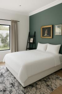 ein großes weißes Bett in einem Zimmer mit Fenster in der Unterkunft Contemporary Constantia Villa of Elegance in Doordrift