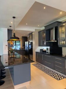 eine Küche mit schwarzen Schränken und einer schwarzen Arbeitsplatte in der Unterkunft Contemporary Constantia Villa of Elegance in Doordrift + 13 Fotos