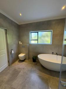 ein Badezimmer mit einer großen Badewanne und einem WC in der Unterkunft Contemporary Constantia Villa of Elegance in Doordrift