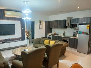 ein Wohnzimmer mit Couch und Tisch und eine Küche in der Unterkunft Embassy Gardens- Frank Homes in Accra