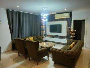 ein Wohnzimmer mit Sofa, Tisch und Stühlen in der Unterkunft Embassy Gardens- Frank Homes in Accra