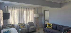 una sala de estar con un sofá y dos sillas en Coastal Bliss Steps from Beach, en Cape Town