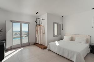 a white bedroom with a bed and a window at Oikos Santorini Living Concept in Fira