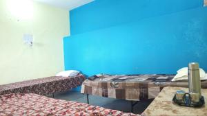 a room with two beds and a blue wall at Himalayan 5 Elements Healing & Ayurveda in Narendranagar