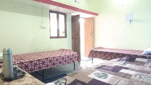 a room with two beds and a table and a window at Himalayan 5 Elements Healing & Ayurveda in Narendranagar