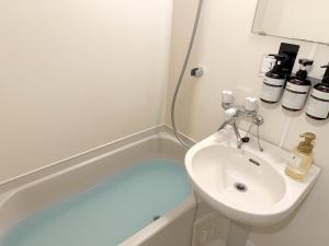 een badkamer met een wastafel en een ligbad bij goom Hotel Haruyoshi in Fukuoka