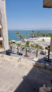 a view of a parking lot with palm trees and the ocean at Kings Apartments in Tiberias