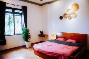 Un dormitorio con una cama con sábanas rojas y una ventana. en Villa Hồng Phúc, en Ấp Thiện Lập