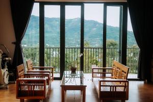 Una habitación con sillas y una mesa y una ventana grande. en Villa Hồng Phúc, en Ấp Thiện Lập