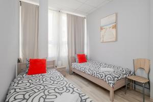 two beds in a small room with red pillows at Hostel Gdynia - Pokoje 2-osobowe na wyłączność in Gdynia