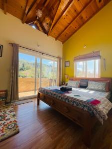 a bedroom with a large bed with a large window at Francolin Lodge-Farmstay @ Darima in Mukteswar