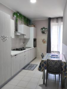 a kitchen with white cabinets and a table with chairs at Nexus 2, Recale, Campania in Recale