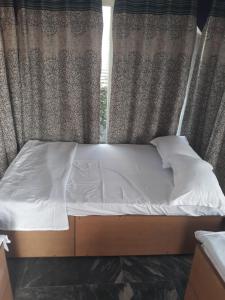 バラナシにあるVaranasi River View Holiday Homestay Dormitory and Hostelの窓際のベッド(白いシーツ、枕付)