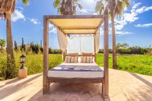 a canopy bed on a patio with palm trees at Villa Es Contes by Slow Villas in Santanyi