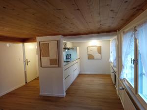 UrnäschにあるGästehaus Rossfall 424 - Self-Check-inの白いキャビネットと木製の天井が備わるキッチン