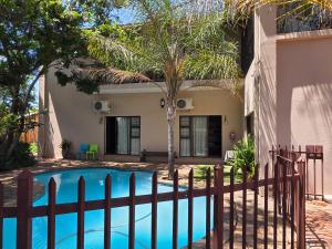 a house with a swimming pool and a fence at Two Bells Guest House in Bloemfontein