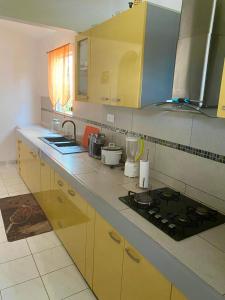 a kitchen with yellow cabinets and a stove top at Hébergement Maison -Les Abymes in Les Abymes
