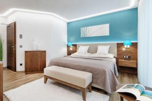 沃尔特湖畔韦尔登Boutiquehotel Wörthersee - Serviced Apartments的卧室里有一张大床，墙壁是蓝色的 更多93张照片