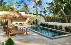 a swimming pool with benches and a thatch umbrella and a swimming pool at Villa Solara in Uluwatu
