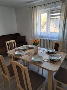 - une table à manger avec des assiettes et des fleurs dans l'établissement Pociechówka apartament, à Tylicz