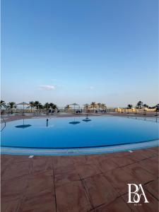 Una gran piscina con palmeras al fondo. en Bel Air -- Sea View Studio, en Ras al Khaimah