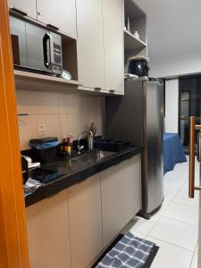 a kitchen with white cabinets and a stainless steel refrigerator at Makia Beach experience 107 D Premium in Ipojuca