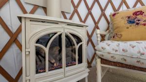 a white fireplace next to a chair with a pillow at Cozy Romantic Yurt Rental in Woodlands near California Beach Town of Cayucos in Cayucos +50 photos