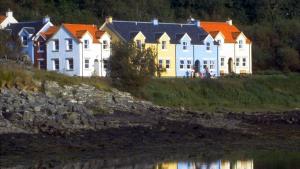 eine Reihe von Häusern auf einem Hügel neben einem Wasserkörper in der Unterkunft Craobh Haven Cottages in Craobh Haven