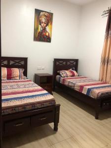 a bedroom with two beds and a painting on the wall at Neema maison de Glamour in Entebbe