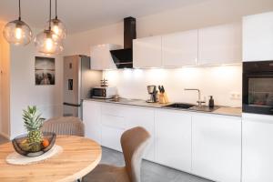 a kitchen with white cabinets and a wooden table at Premiumzeit Pure Apartment Bostalsee mit Infrarotkabine in Nohfelden