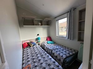 two beds in a small room with a window at Mobilhome neuf au camping La Réserve in Gastes