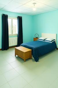a blue bedroom with a bed and a table at L'Arbre de Vie in Montmarault