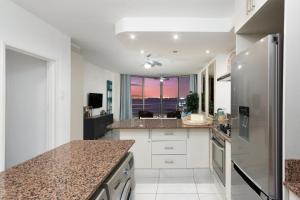 Una cocina con gabinetes blancos y una ventana grande. en Seaside Sunsets, en Strand