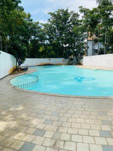 a large blue swimming pool with trees in the background at Ponni Delta Nature Stay by the River in Fort