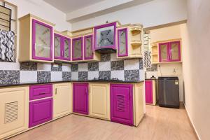 a kitchen with purple cabinets and a tile wall at Immanuel Homestay, Kalathipady, Kottayam, Flat E in Kottayam