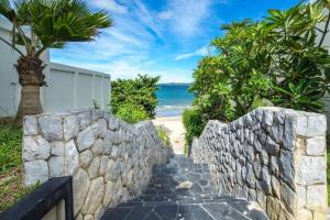 a stone path leading to a beach with a stone wall at 3BR Pool Villa Beach Access Patumnak Hill in Pattaya South