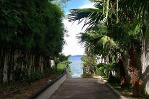 a path with palm trees and the ocean in the background at 3BR Pool Villa Beach Access Patumnak Hill in Pattaya South